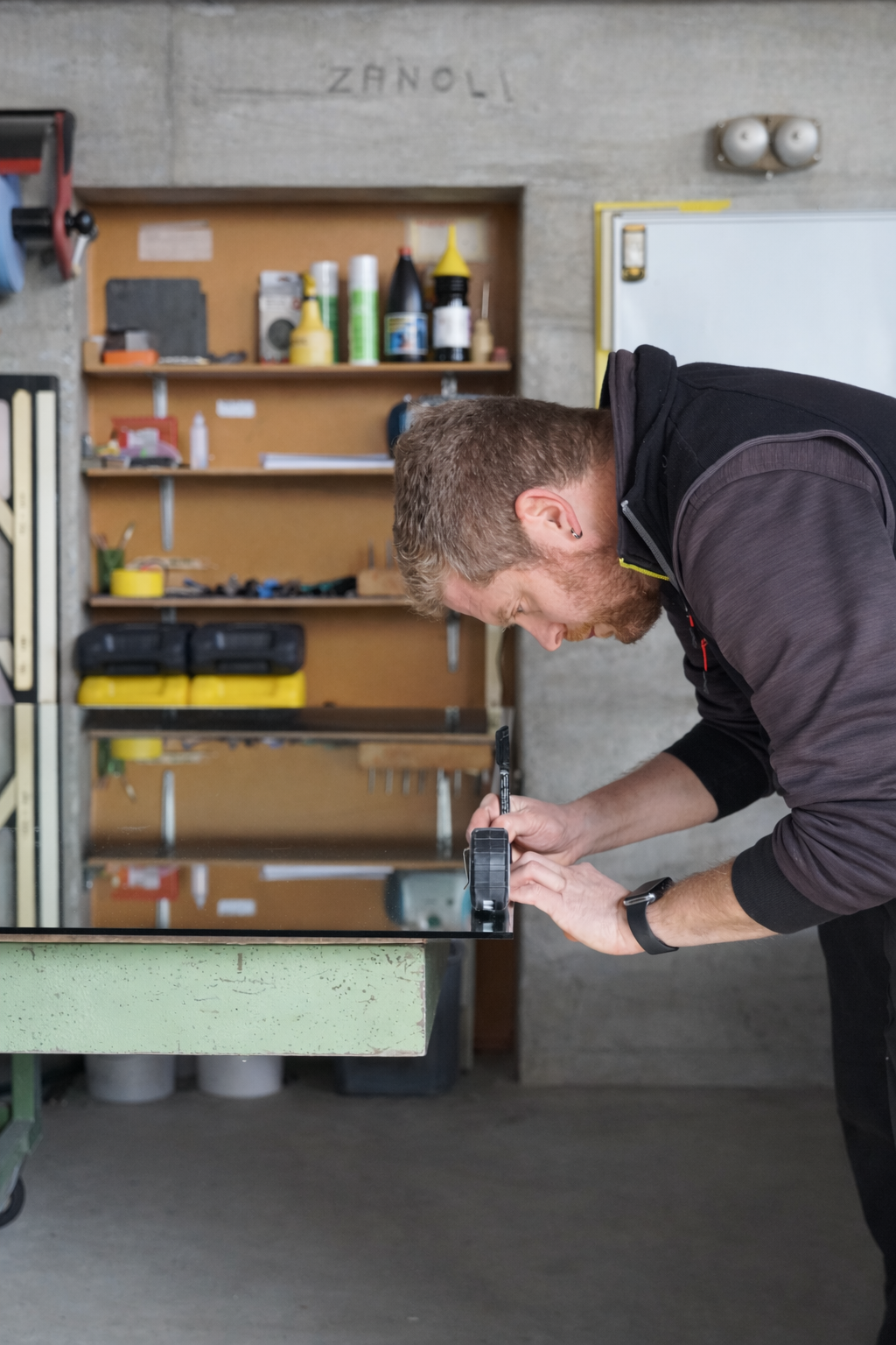 Artisan vitrier découpant une plaque de verre en atelier pour réalisation sur mesure.